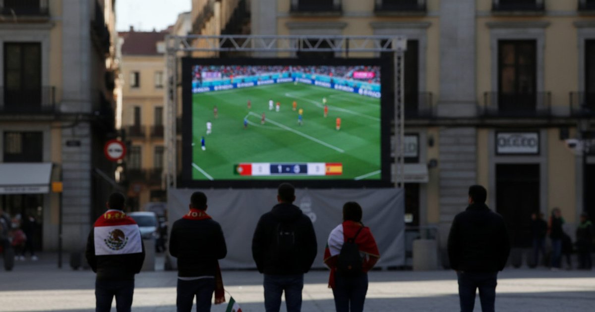 Aficionados latinos en España siguen atentamente un partido crucial del Mundial 2026 en una pantalla pública.