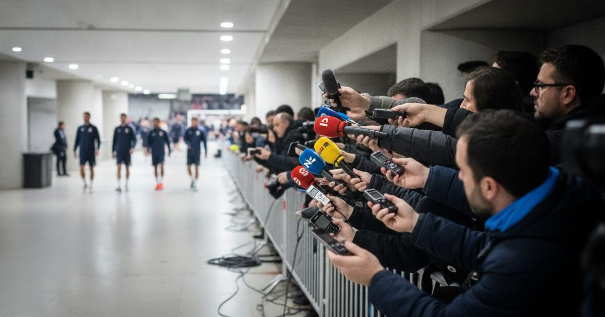 Periodistas y camarógrafos en la zona mixta de un estadio cubriendo la salida de los equipos tras un partido amistoso internacional.